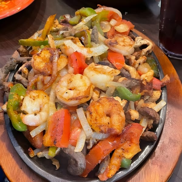 Sizzling El Agave Mexican Grill fajitas with shrimp, steak, bell peppers, and onions on a hot platter.